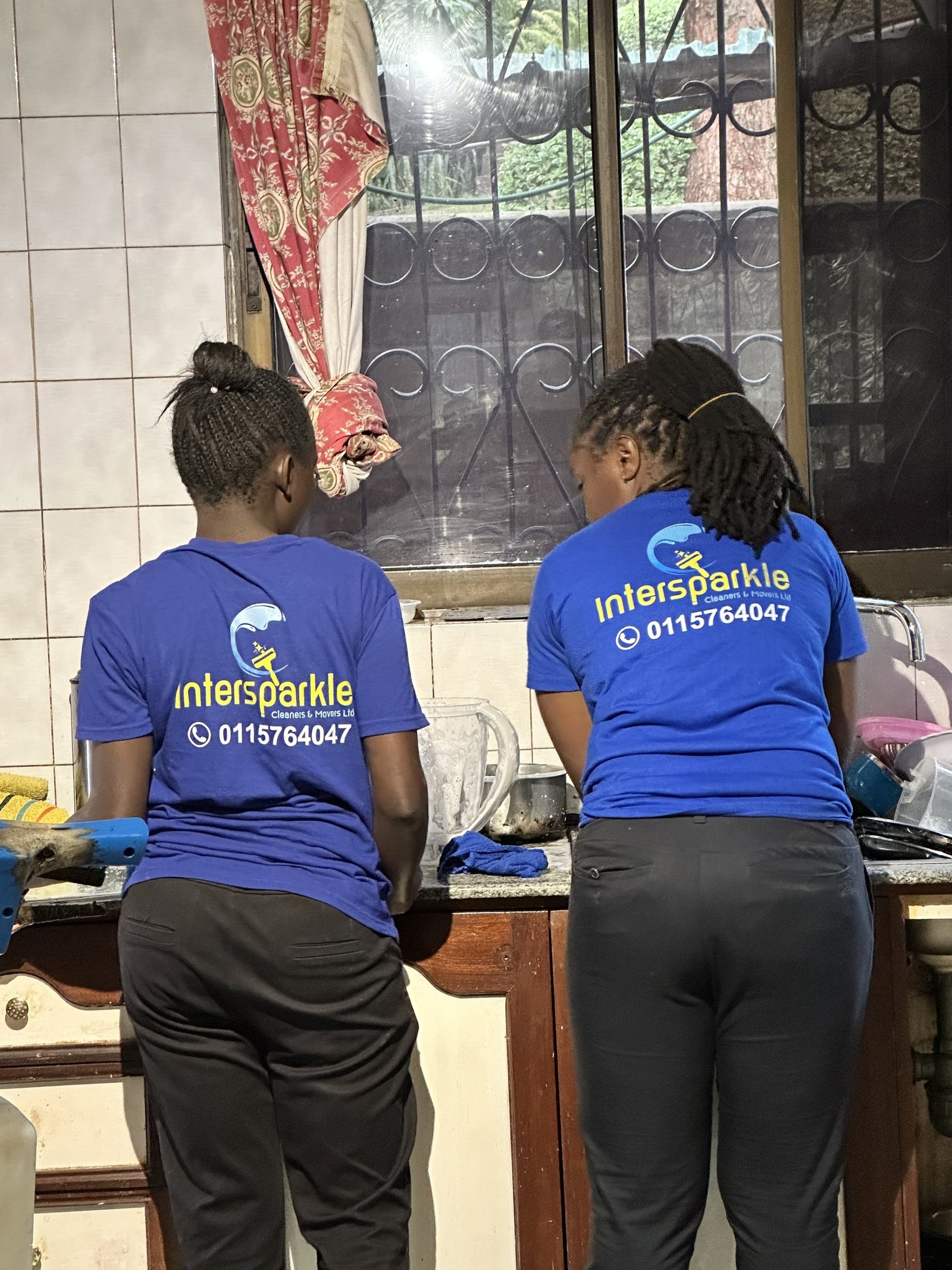 Two cleaners scrubbing a kitchen counter