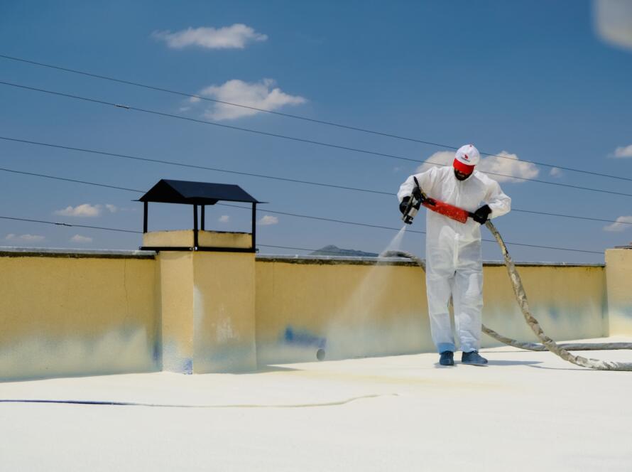 a man in a white coverall spray painting a roof